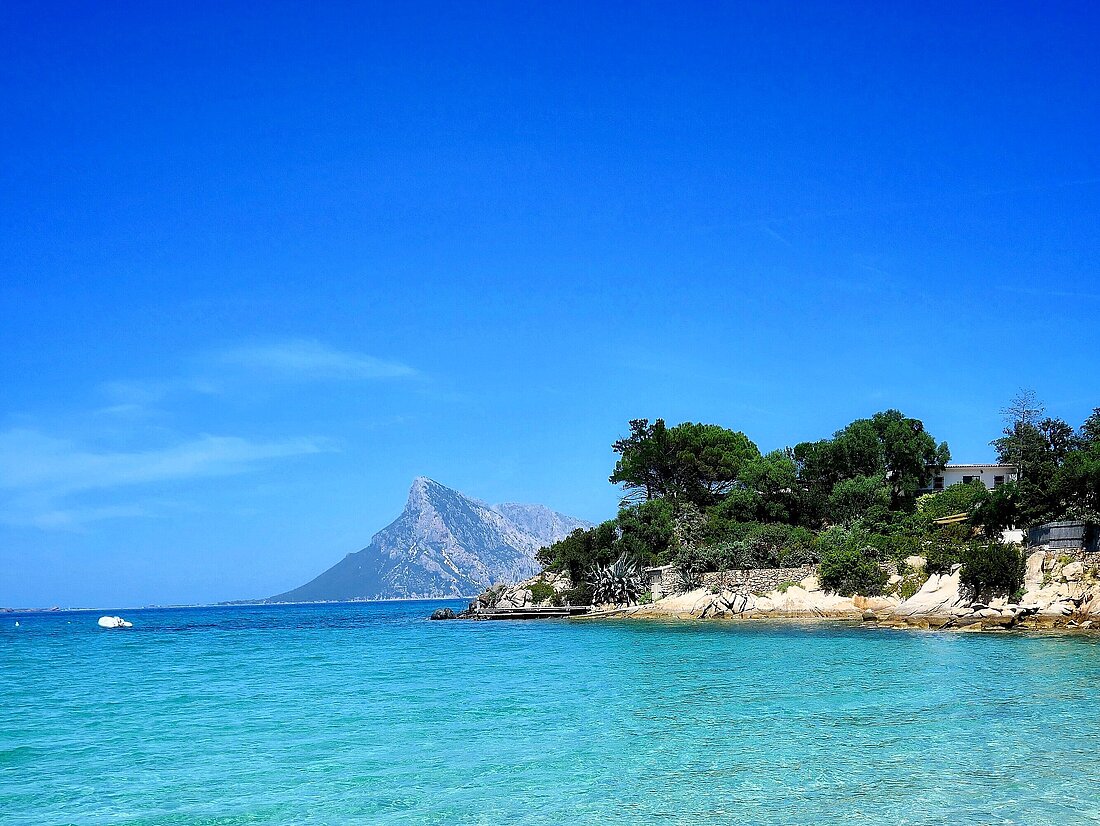 Blick vom Strand auf kristallklares Wasser und Landzungen vor Olbia