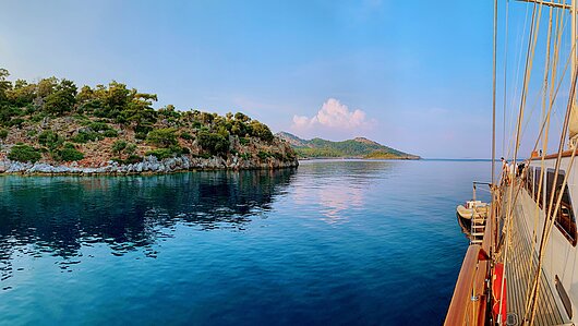 Blick von einer großen Yacht auf steinige Buchten und klares, blaues Wasser Blick von einer großen Yacht auf steinige Buchten und klares, blaues Wasser