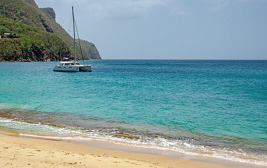 Katamaran ankert vor weißem Strand in Bequia