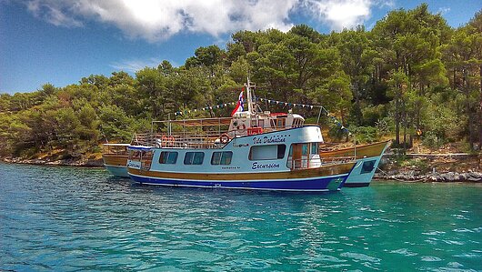 Yacht vor einer Bucht auf Kornati mit tĂĽrkisem Wasser bei blauem Himmel