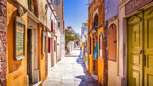 Sonnenbeschienene Gasse in Griechenland mit bunten Häusern