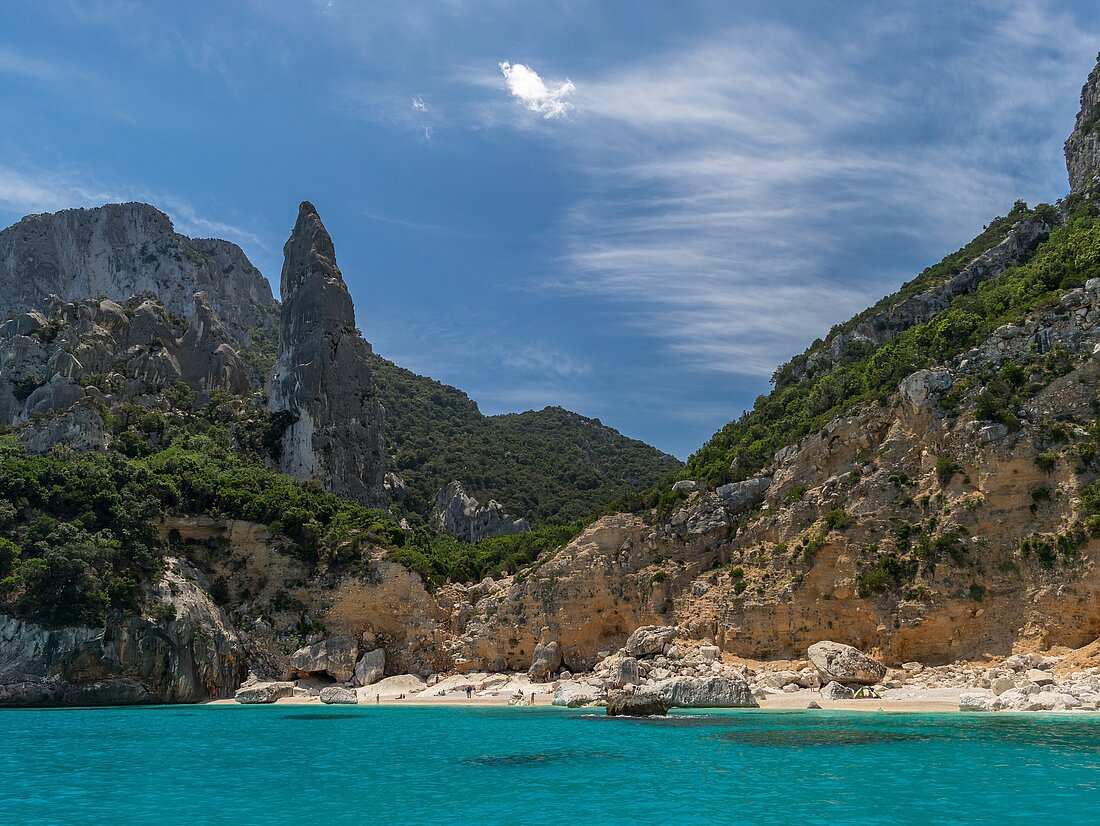 Sandstrand vor Felsklippen mit blauem Wasserim Vordergrund