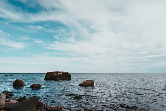 Blick auf die Ostsee und den Horizont sowie dunkle Steine im Wasser Blick auf die Ostsee und den Horizont sowie dunkle Steine im Wasser