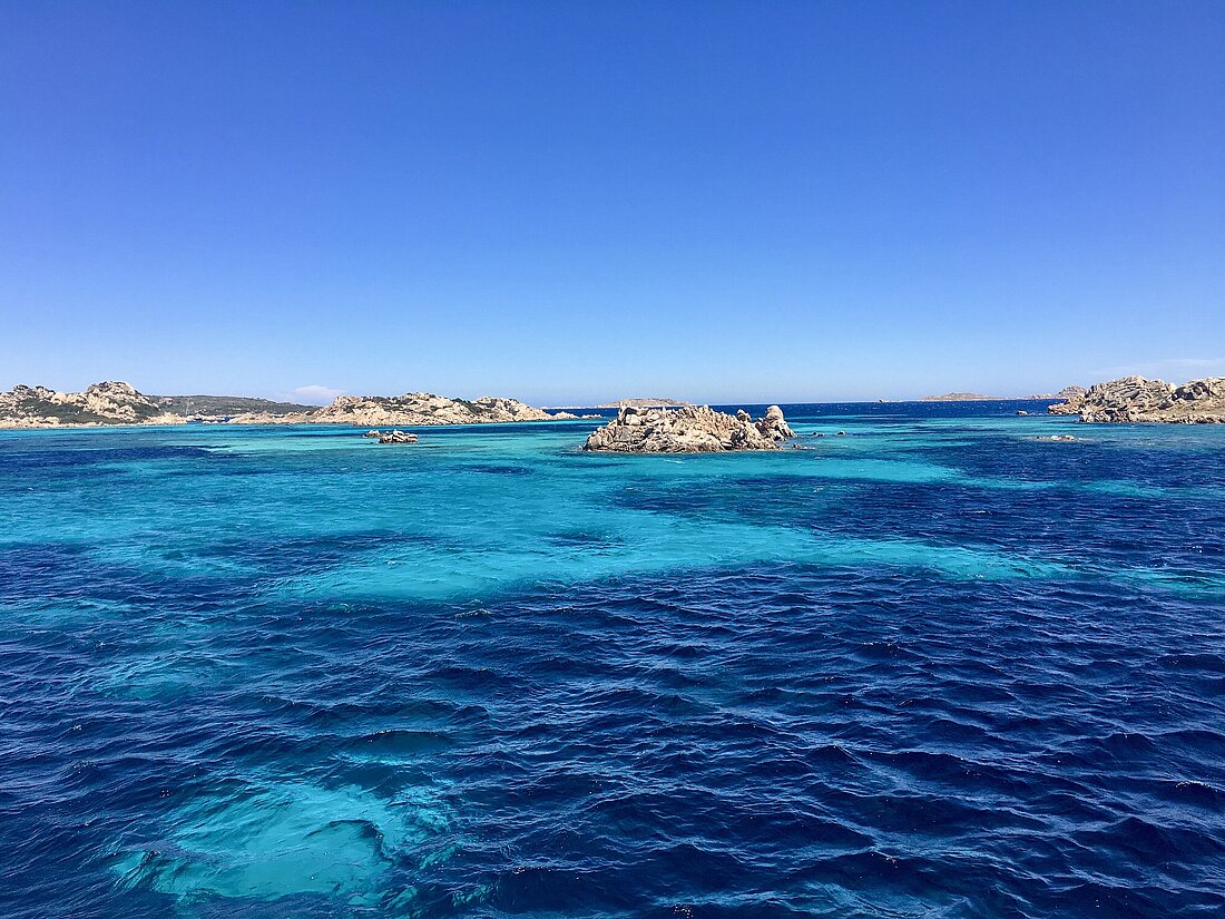 Zwischen Felsen im Wasser schimmert das türkisblaue Meer