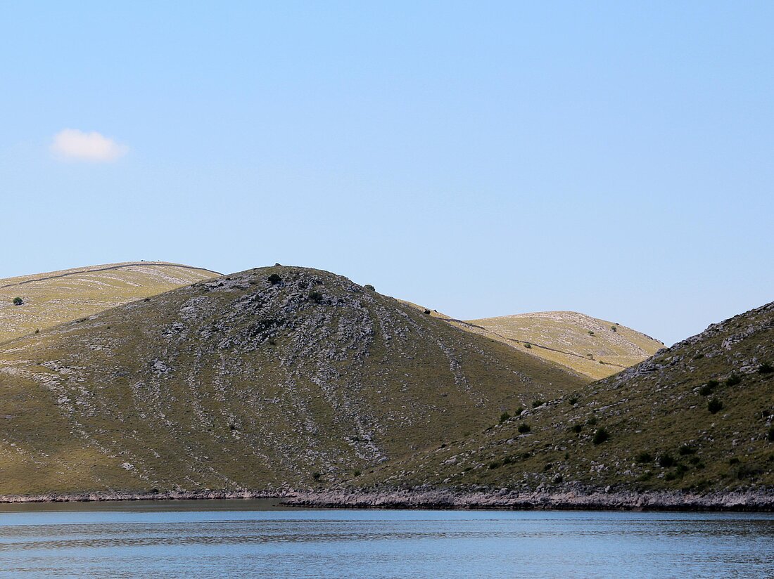 Das blaue Meer und eine karge Felseninsel der Kornaten im Hintergrund