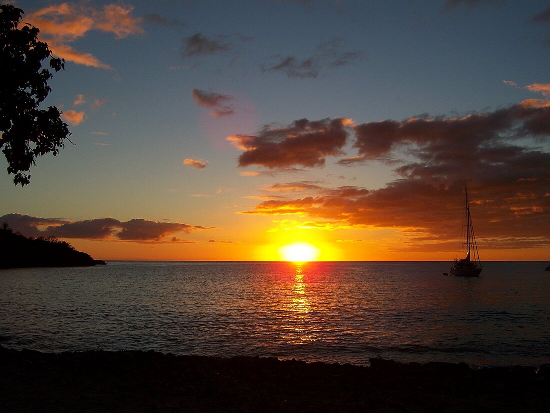 Sonnenuntergang über dem Meer mit einer Segelyacht im Vordergrund