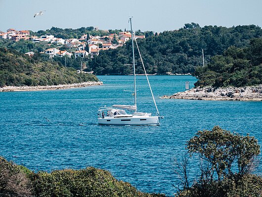 Segelyacht im klaren, blauen Meer vor Pula, umgeben von Landzungen und Häfen