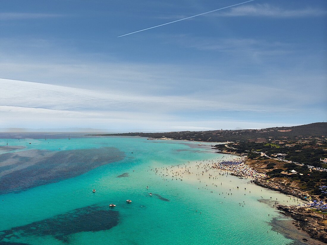 Weißer Sandstrand mit Touristen, türkisblauem Wasser und Yachten die davor ankern