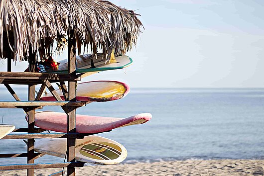 mehrere bunte Surfbretter in einer exotischen Hütte am weißen Strand von Martinique mehrere bunte Surfbretter in einer exotischen Hütte am weißen Strand von Martinique