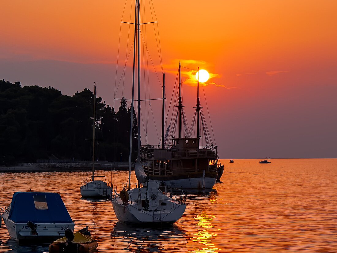 Blick vom Hafen auf Segelyachten und Motorboote im Sonnenuntergang der Kornaten