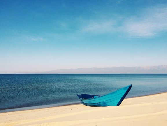 paradiesischer, weißer Sandstrand in Kuba, Blick auf das Meer, den Horizont und ein blaues Boot paradiesischer, weißer Sandstrand in Kuba, Blick auf das Meer, den Horizont und ein blaues Boot