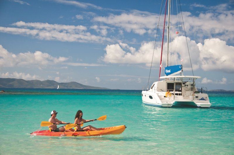 Blick von der Küste auf türkises Meer mit Yacht und Touristen, die Kayak fahren Blick von der Küste auf türkises Meer mit Yacht und Touristen, die Kayak fahren